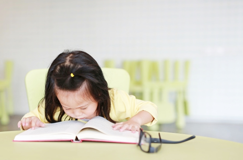 short-sighted-little-child-girl-reading-book-kids-room_38678-203