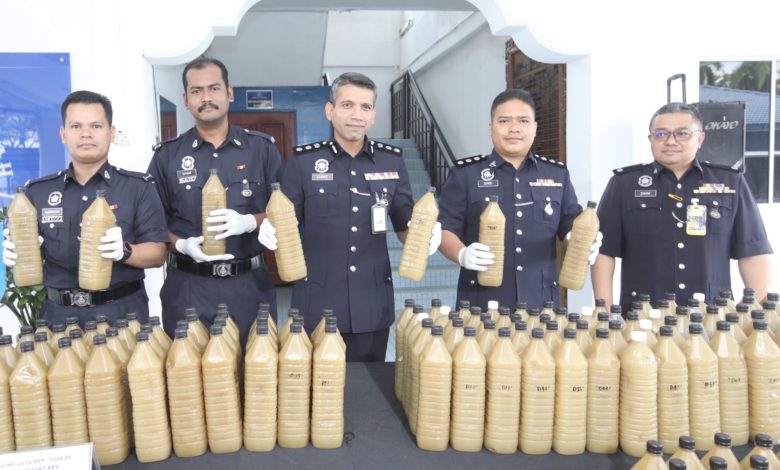 聶依查尼（中）與建功警官展示警方逮捕嫌犯後，所起獲的瓶裝哥冬水，每瓶售價約20令吉。