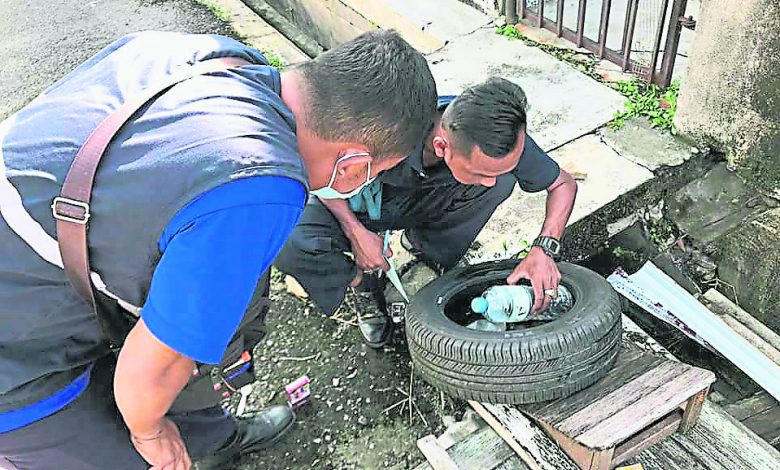 執法員仔細檢查舊輪胎，確保沒有孑孓在裡頭。