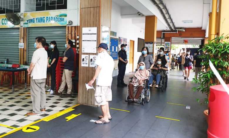新加坡選民戴上口罩，在與他人保持社交距離的情況下排隊進入投票站。（馬新社圖）
