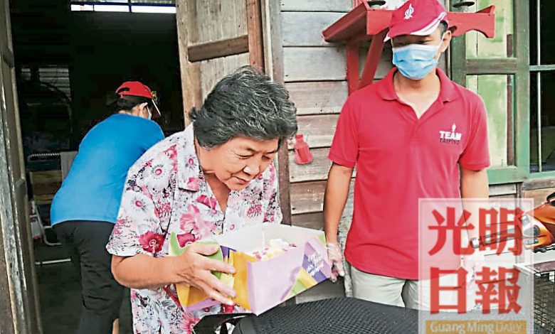 老婆婆在獲得母親節蛋糕時喜極而泣，右是峇登村長吳錫標。