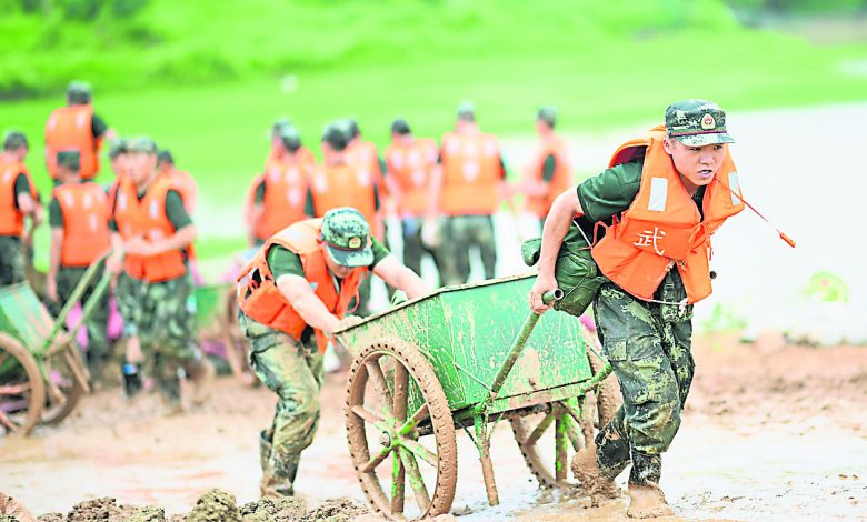 參與抗洪搶險的武警官兵，在鄱陽縣昌江圩利用推車運送沙袋，加固堤壩。