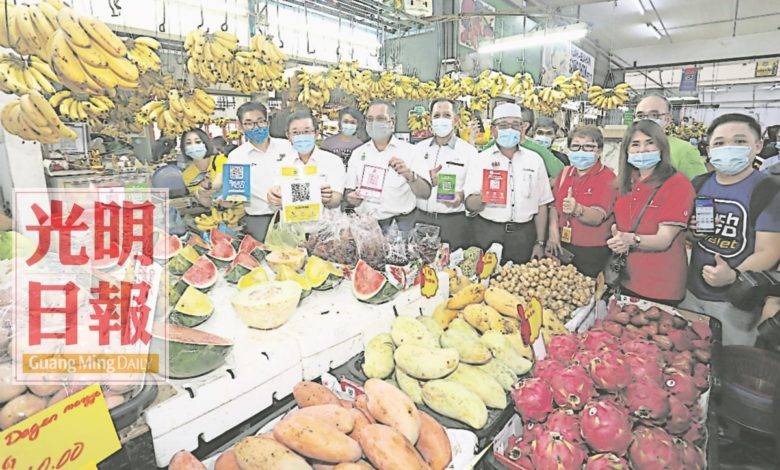 沈志勤（左二起）、曹觀友、佳日星、阿都哈林、羅查里到峇央峇魯巴剎裡一個接受數種電子錢包的水果攤視察情況。