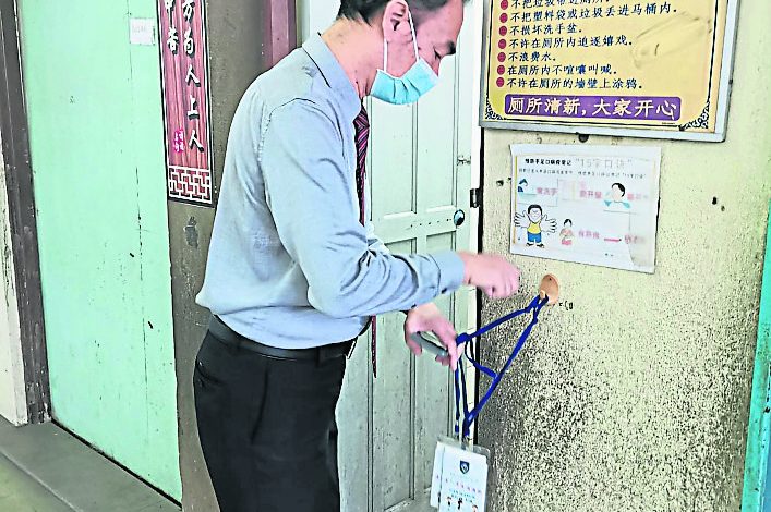 陳國山展示學生上廁所時必須佩戴的名牌，若廁所外沒有掛上名牌則不能進廁所。