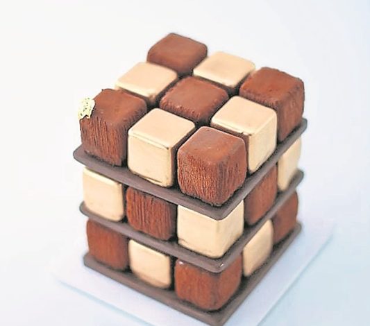 這道作品魔方（Rubik）是使用花色小蛋糕（Petit Four）或一口甜點的概念推出。想讓顧客跳出一個框架，生日蛋糕不一定是圓的，也可以是小小的甜點拼成一個完整的蛋糕。
外層是法國巧克力，再來是法國的70%巧克力慕斯，接着，為添加更細膩的脆口感，他採用了榛果果仁糖（Hazelnut Praline），以海綿蛋糕做基底。