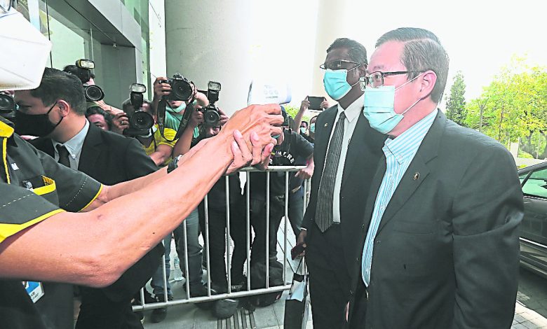 林冠英（右起）在雷爾陪同下抵達布城反貪會總部，兩人在大門前接受體溫檢測。