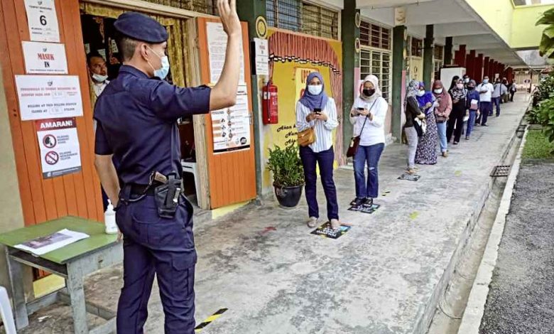 駐守在投票室外面的警員促請選民保持人身距離。