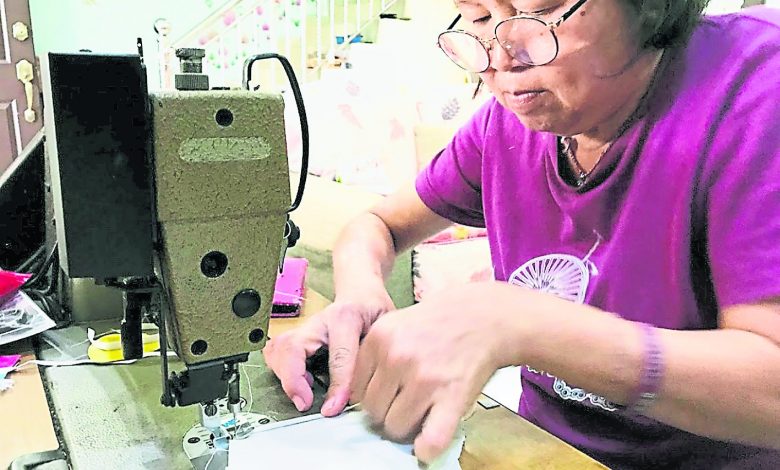 家庭主妇用缝纫机缝制布口罩。