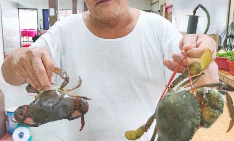 王清煌展示肥碩的沼澤蟹與海蟹，螃蟹是該餐廳的招牌菜。