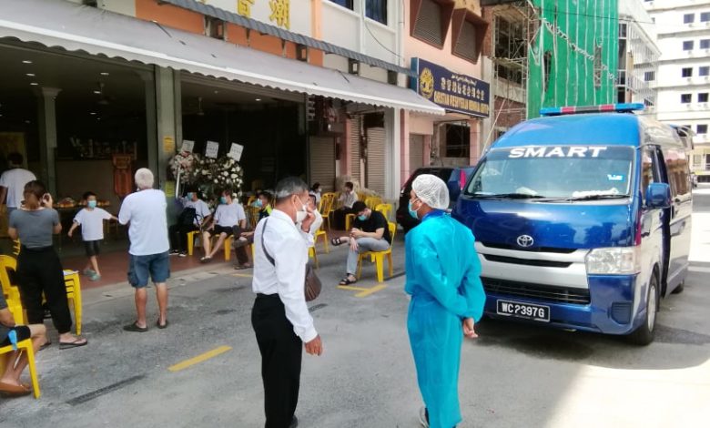 救護車和醫護人員在殯儀館外準備將吳佩玉載去隔離中心。

