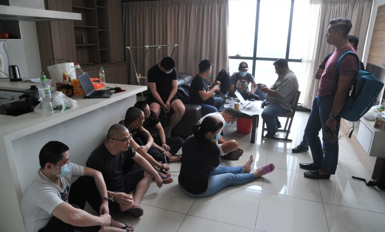 涉嫌網絡賭博集團工作的13名中國男女，坐在地上等待警方發落。
