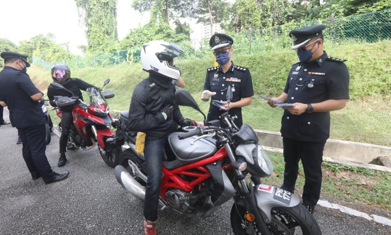 警方派發防範詐騙案宣傳單給路過摩托車騎士。