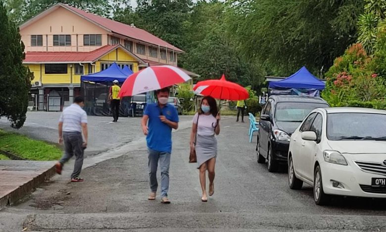 古晉市區開始下起細雨，選民們撐傘去投票。