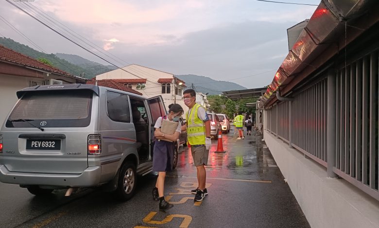 檳華小學愛心家長團成員，在學校側門協助學生下車。