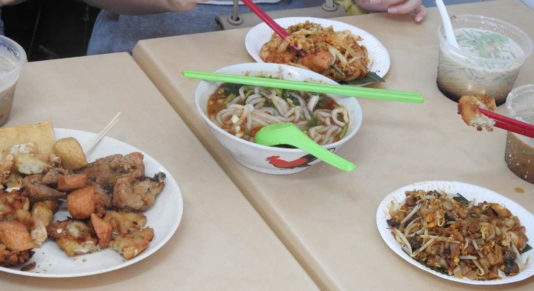 遊客叫來滿桌的美食，前左是炸鹵肉，前右為炒粿條，中間的是叻沙，右上角為煎蕊。