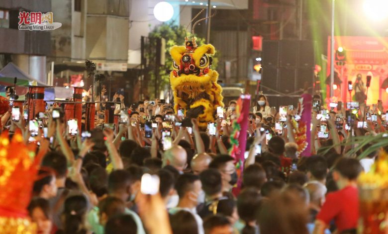 圍觀群眾高舉手機拍下精湛的高樁舞獅表演。