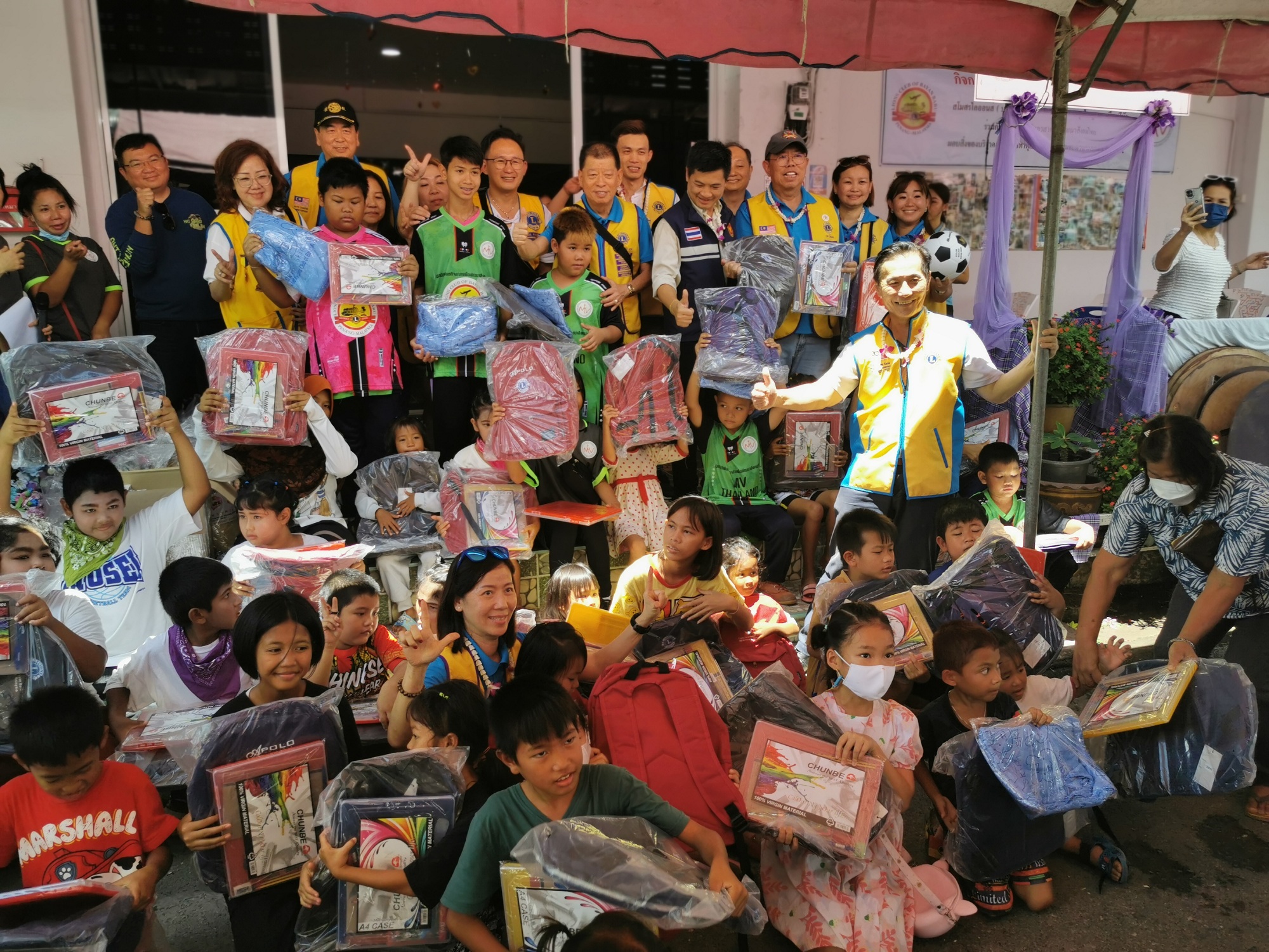 The children happily took a group photo after receiving their schoolbags and stationery.