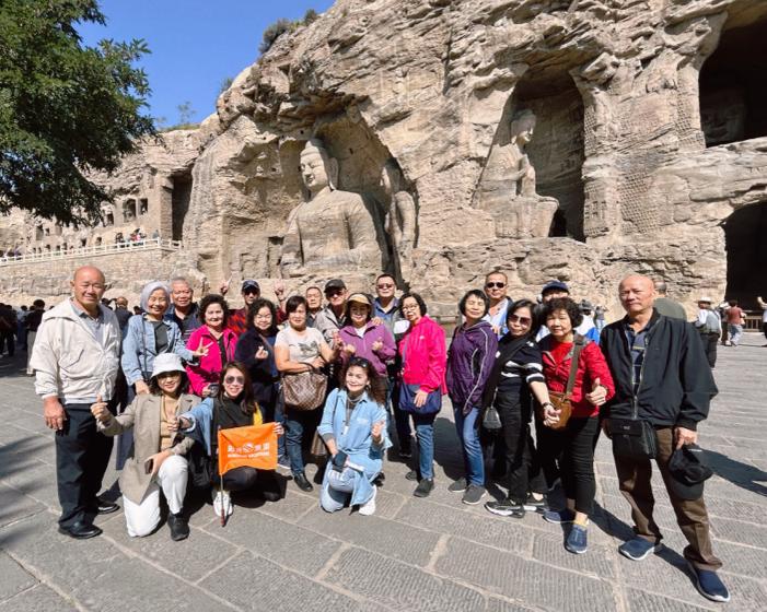 The first group of tourists took a group photo in front of the iconic Buddha statue of Yungang Grottoes.
