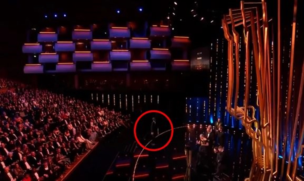  惡作劇男子（紅圈處）趁台上劇組向台下其他演員喊話時，從另一側跑上台。