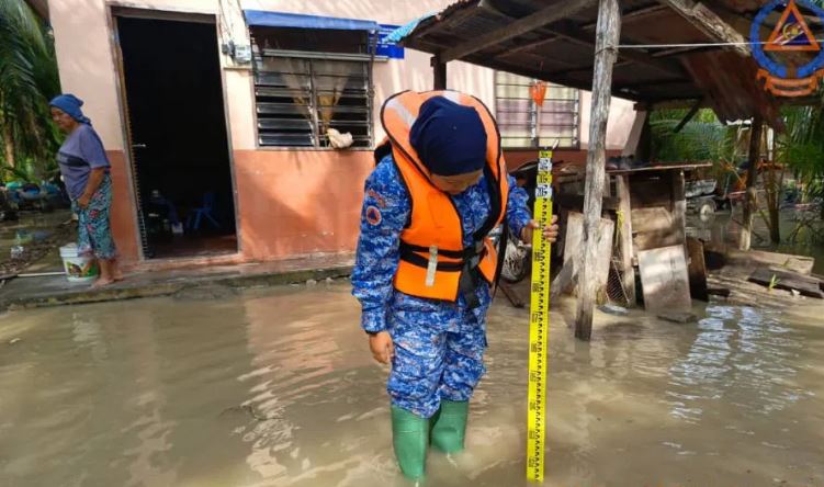 民防部隊隊員測量當地的水位高度。（峇眼拿督民防部隊提供）