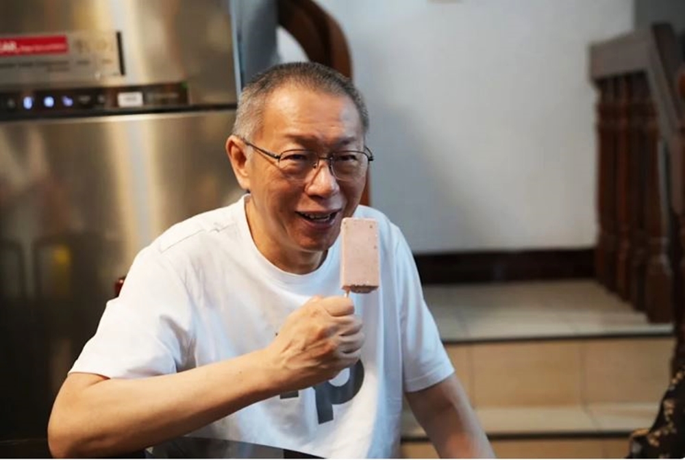 柯文哲坐在餐桌旁,手裡拿著冰棒露出笑容