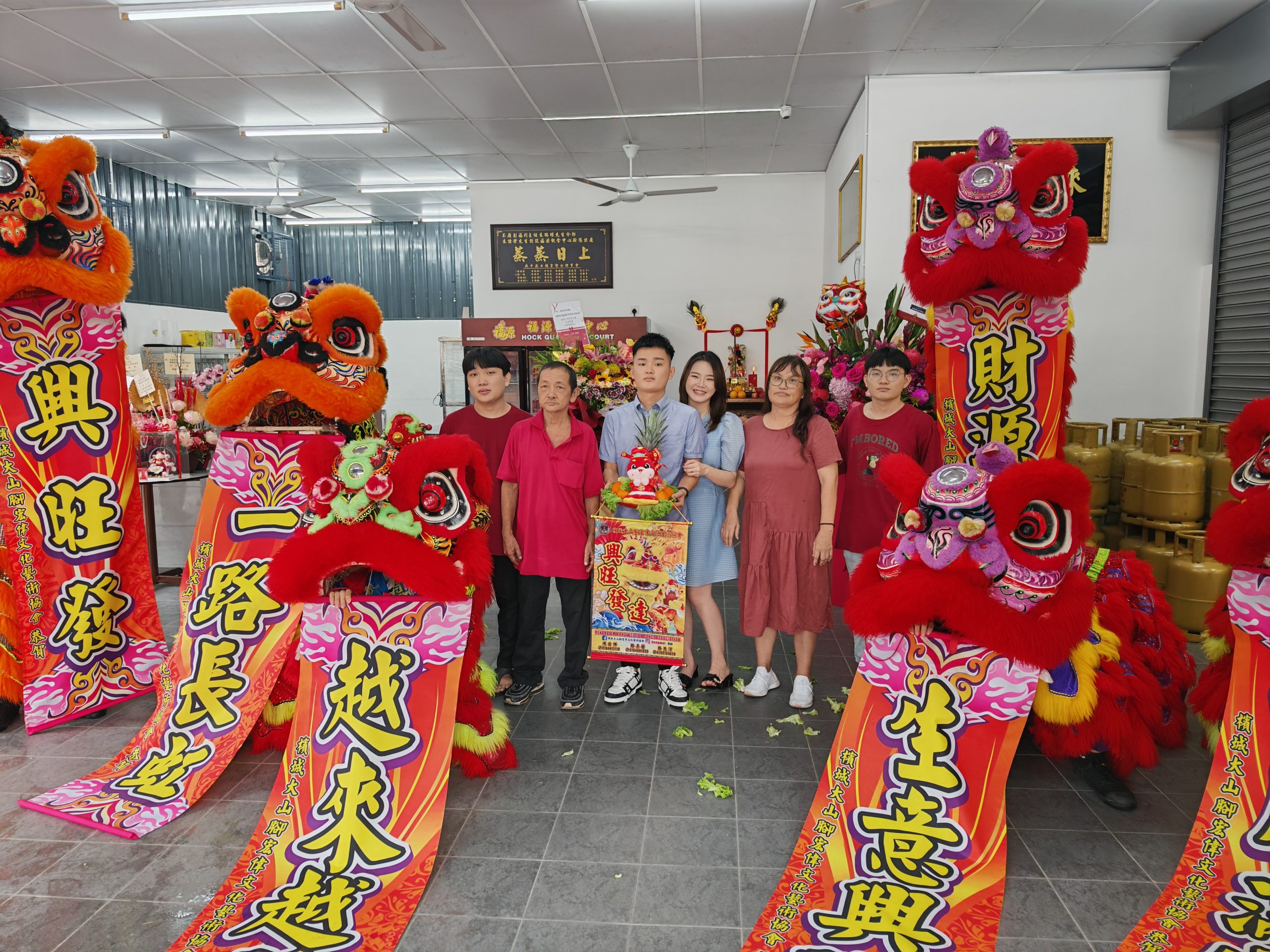 朱俊荣夫妇接领舞狮的吉祥品及黄梨后、与朱瑞明（左二）、潘明华（右二）及家人合影。