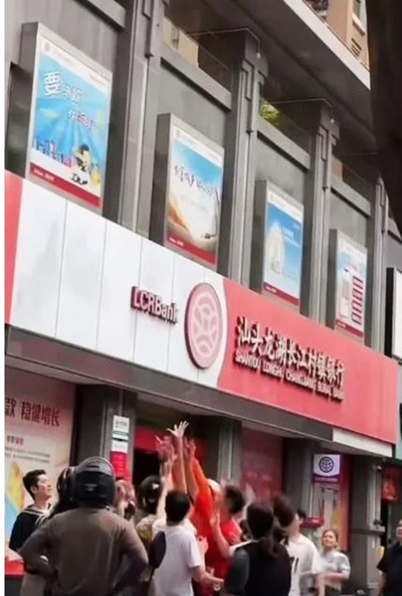 在汕头市合信·星湖城小区，有一名中年妇女从窗户口下大量纸币，引来途人疯抢。（视频截图）