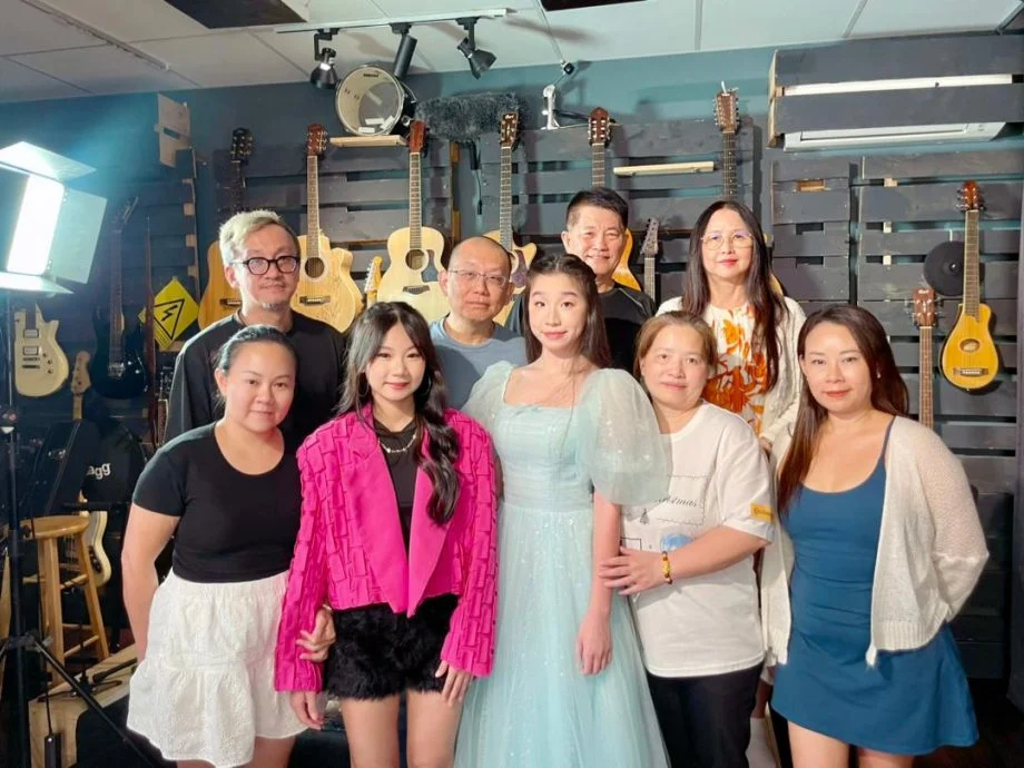 张莉琦（前排左二起）和陈诗盈与家人赛前合影；后排右起为公会财政陈碧燕和秘书长陈维通到场支持。（马来西亚华人演艺人公会供图）