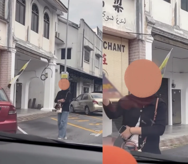 视频中，当行车记录仪车主准备将车停入该车位时，女子似乎摆出“不能停”的手势，试图阻止对方停车，但车主并未理会，依旧将轿车停在那里。（视频截图）