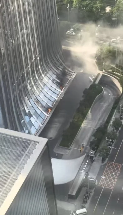 一架编号为B-12PP的小型飞机周五下午撞上中信大厦东面高层后在空中解体，碎片散落一地，其中部分残骸掉落在大厦东门簷篷上起火。（影片截图）
