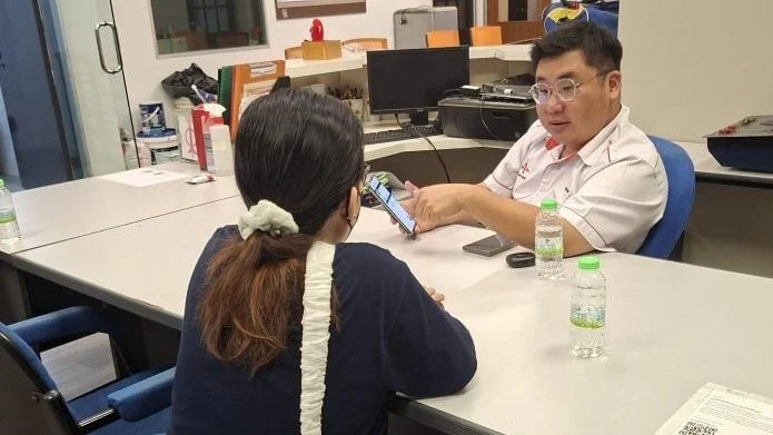 女子向李文彬（右）叙述报考摩托车驾照，却误坠诈骗集团精心设计的“连环骗局过程。