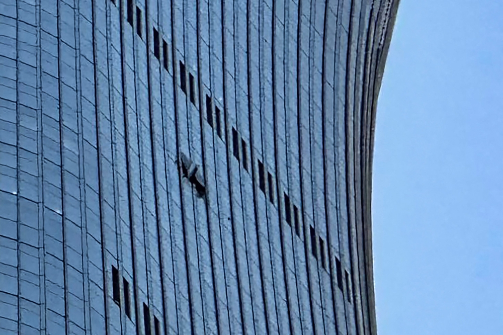 大厦玻璃幕墙被撞部分受损。飞机撞击后在空中解体,碎片散落在大厦附近。(法新社档案照片)