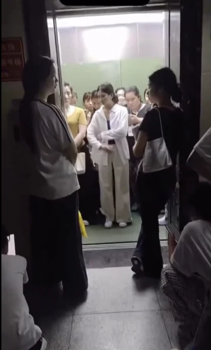 一群女子搭乘电梯时，因人数超载触发警报，但没人愿意让出，场面僵持不下。（视频截图饿）