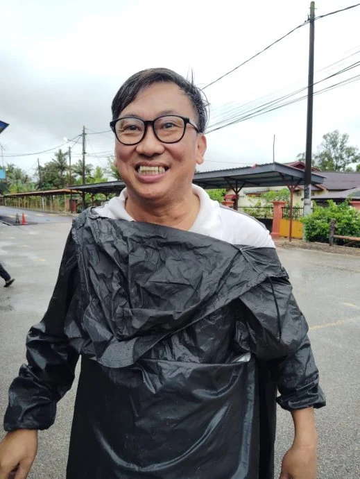 黄天祥穿着雨衣，骑摩托车到投票中心履行公民责任。