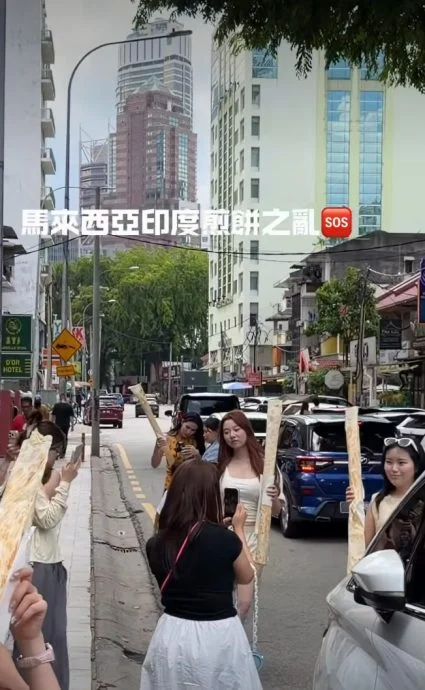 中国女游客的打卡举动已更加升级,直接用手“握住”Roti tisu,走到店外的人行道上拍照。(视频截图)