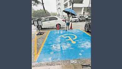 Photo of 妇女抱孩子雨中等候 电召车司机撑伞接上车