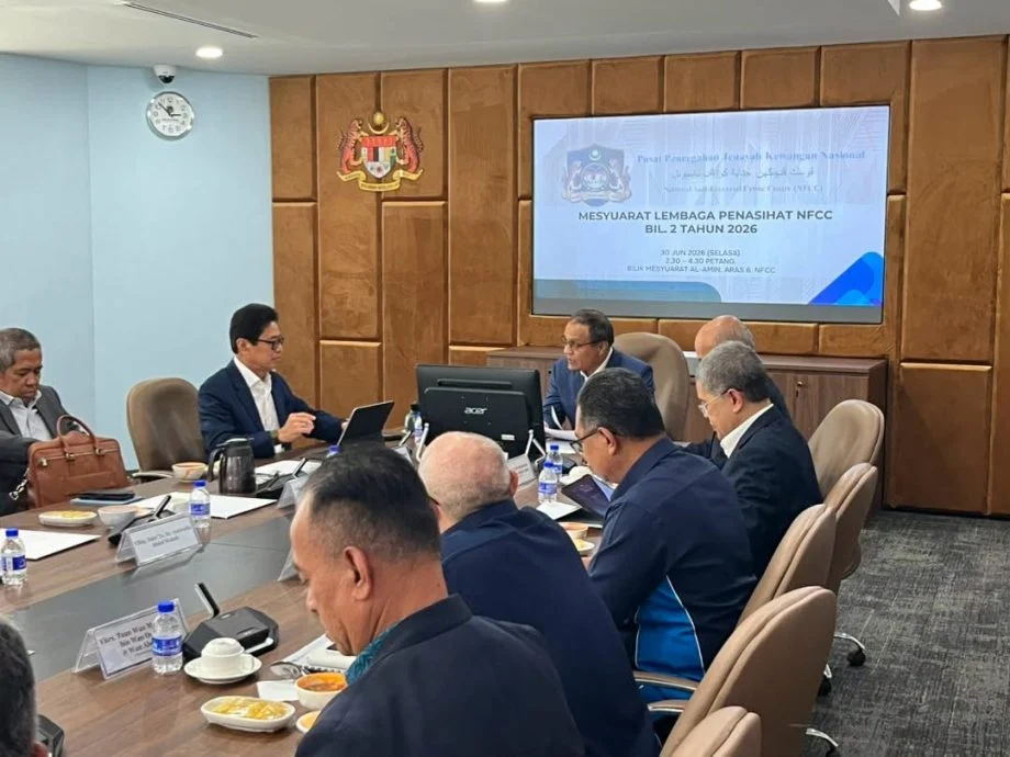 阿占巴基（左）在国家金融罪案预防中心顾问委员会会议上，与莫哈末杜苏基互动。 （总检察署脸书）